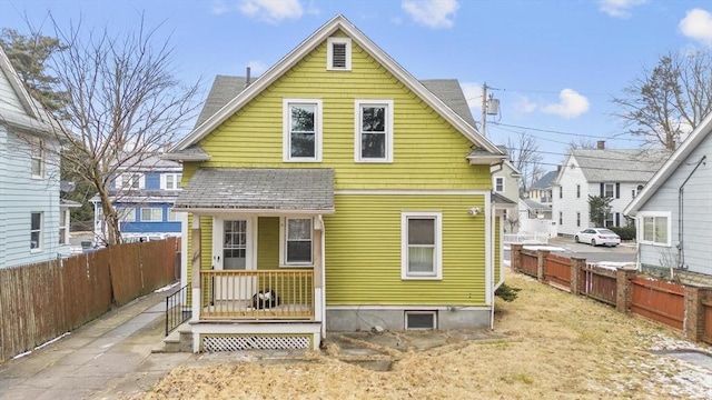 rear view of house featuring roof with shingles and fence