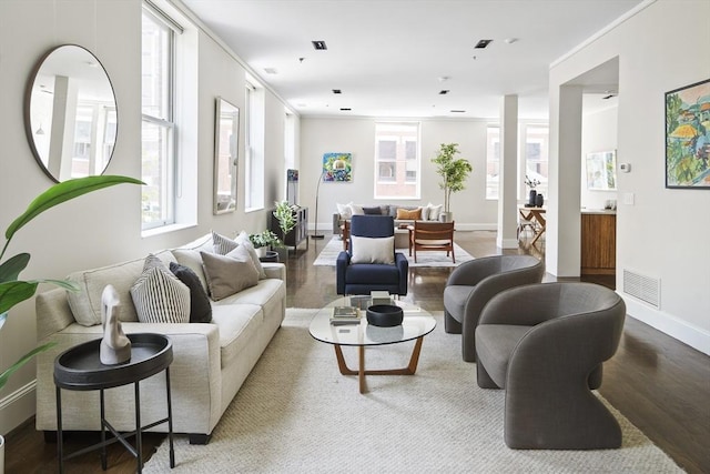 living room with baseboards, crown molding, visible vents, and wood finished floors