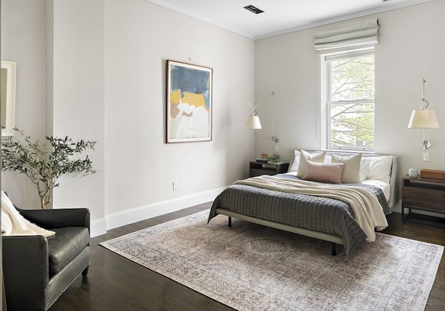 bedroom with crown molding, visible vents, dark wood finished floors, and baseboards