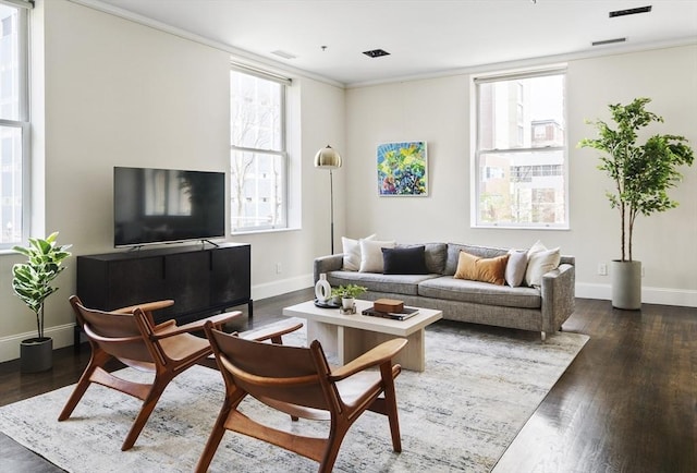 living area with visible vents, baseboards, wood finished floors, and ornamental molding