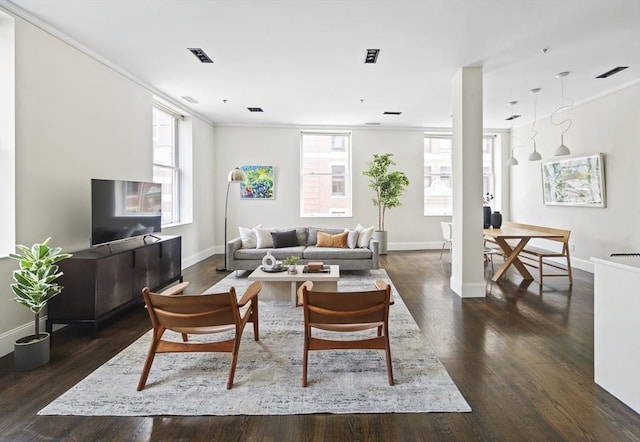 living area with crown molding, dark wood-style flooring, visible vents, and baseboards