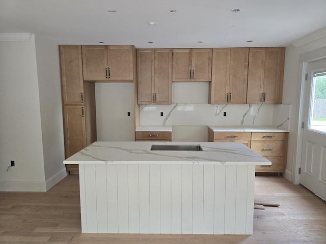 9 Swan St Unit 3, Beverly, MA 01915 - kitchen featuring light wood-style floors, baseboards, a kitchen island, brown cabinetry, and light stone countertops