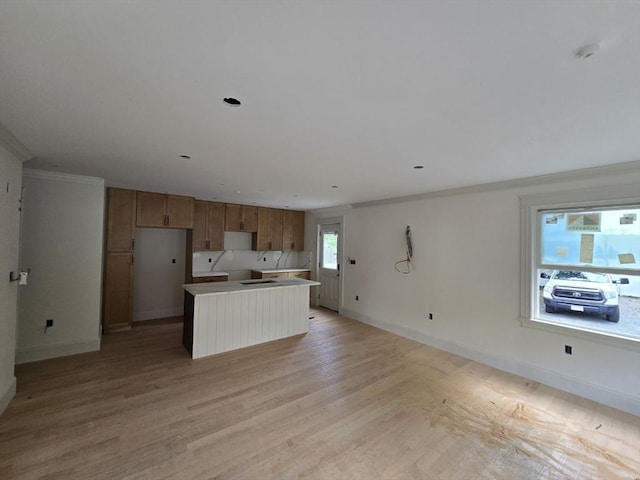 9 Swan St Unit 3, Beverly, MA 01915 - kitchen with a kitchen island, baseboards, brown cabinetry, light wood finished floors, and crown molding