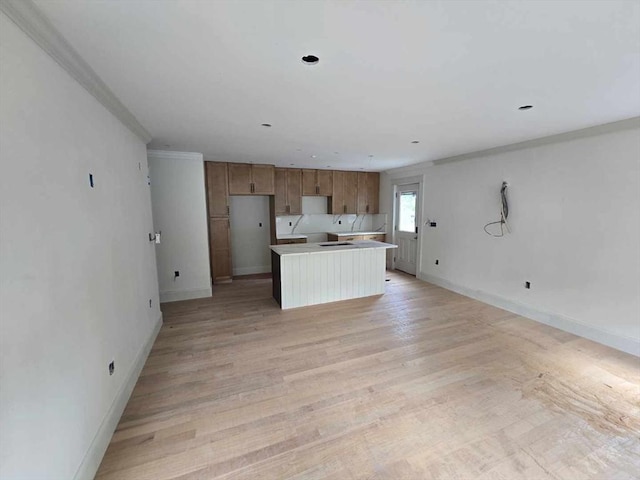 9 Swan St Unit 3, Beverly, MA 01915 - kitchen featuring brown cabinetry, a center island, baseboards, light wood-type flooring, and light countertops