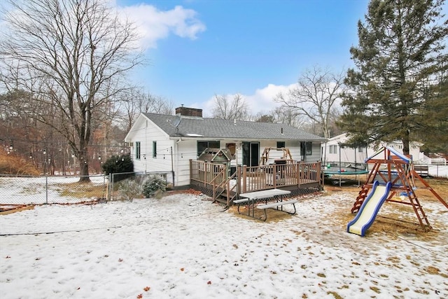 snow covered rear of property featuring a playground and a trampoline