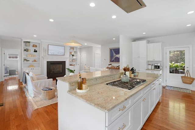 kitchen featuring stainless steel gas stovetop, a fireplace, recessed lighting, a center island, and white cabinets
