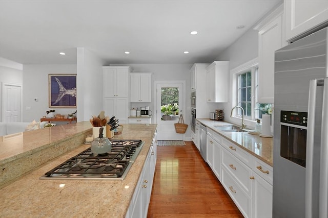 kitchen with stainless steel appliances, a sink, white cabinetry, wood finished floors, and recessed lighting