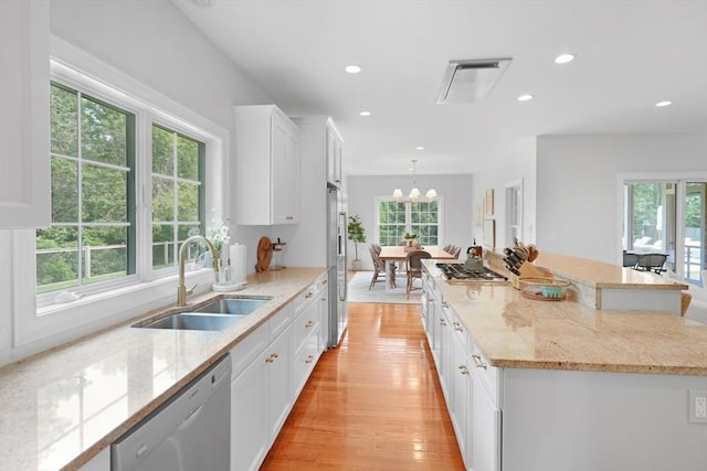 kitchen with a sink, stainless steel appliances, white cabinets, recessed lighting, and light wood-style floors