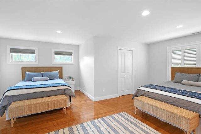 bedroom with light wood-style flooring, recessed lighting, baseboards, and a closet