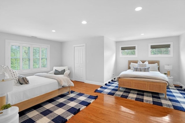 bedroom with wood finished floors, multiple windows, baseboards, and recessed lighting