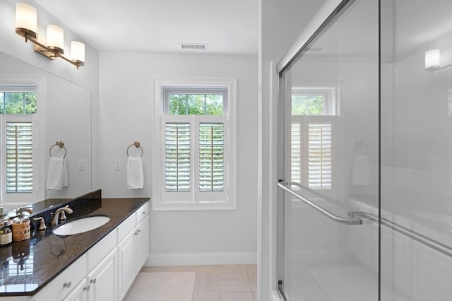 bathroom featuring healthy amount of natural light, a shower stall, baseboards, and vanity