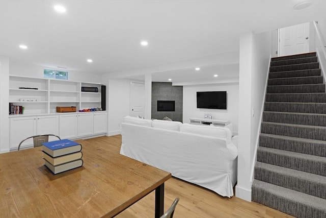 living area with stairs, a fireplace, light wood-style floors, and recessed lighting