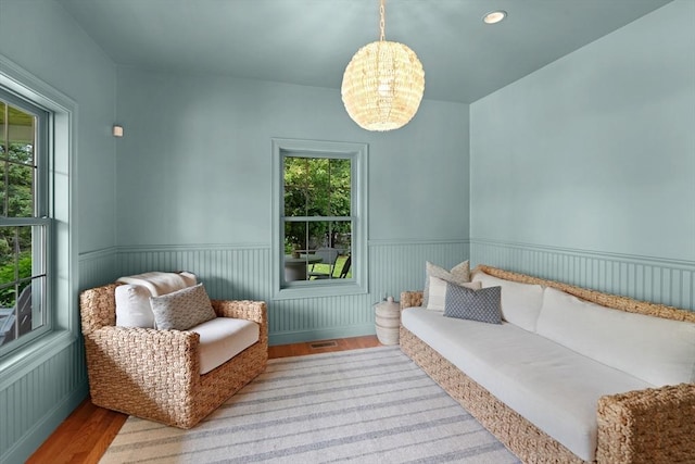 sitting room featuring wood finished floors, a chandelier, and a wainscoted wall