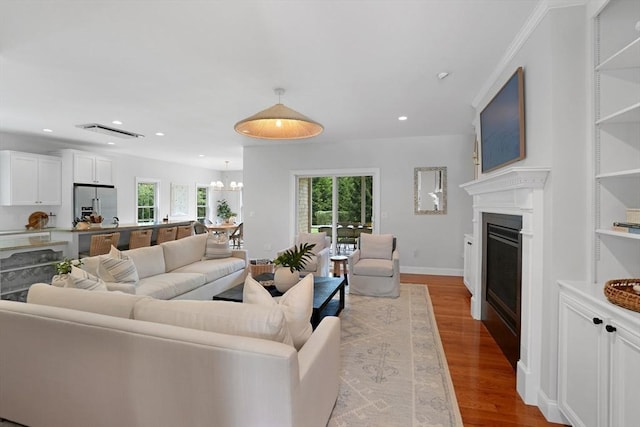 living room featuring a fireplace, wood finished floors, recessed lighting, a chandelier, and baseboards