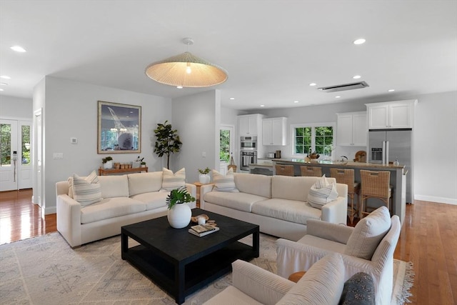 living area featuring light wood-style flooring, recessed lighting, and baseboards