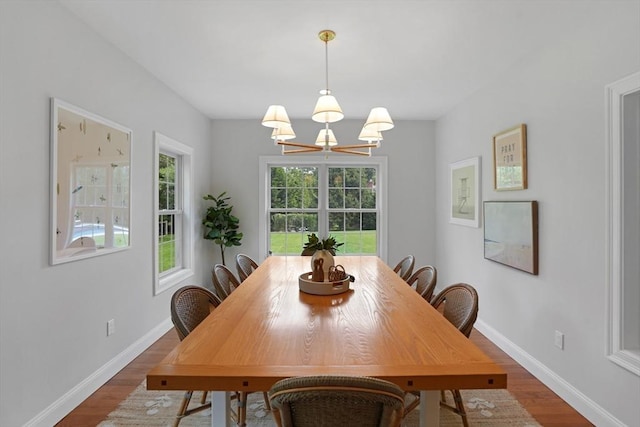 dining area with a chandelier, dark wood-style flooring, and baseboards