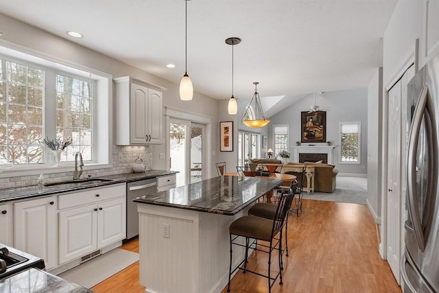 kitchen featuring sink, appliances with stainless steel finishes, a kitchen island, pendant lighting, and white cabinets