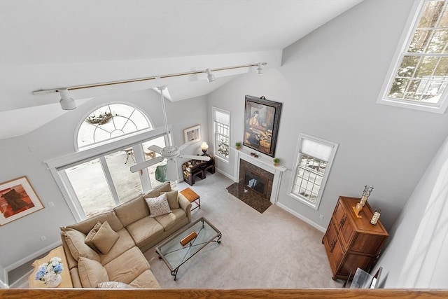 living room featuring light colored carpet, a healthy amount of sunlight, a premium fireplace, and track lighting