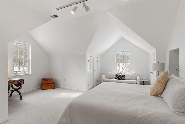 bedroom with light carpet, track lighting, and lofted ceiling