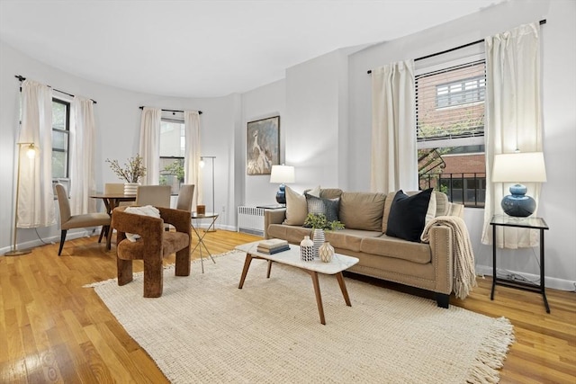 living area with light wood-type flooring, baseboards, and radiator