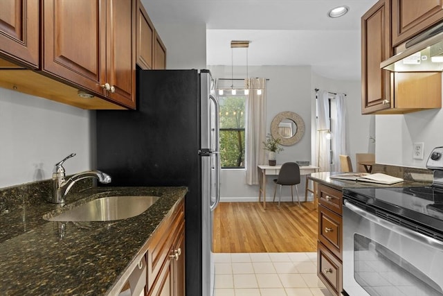 kitchen featuring stainless steel range with electric cooktop, under cabinet range hood, a sink, brown cabinetry, and light tile patterned floors