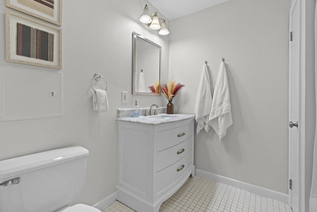 bathroom featuring toilet, baseboards, and vanity