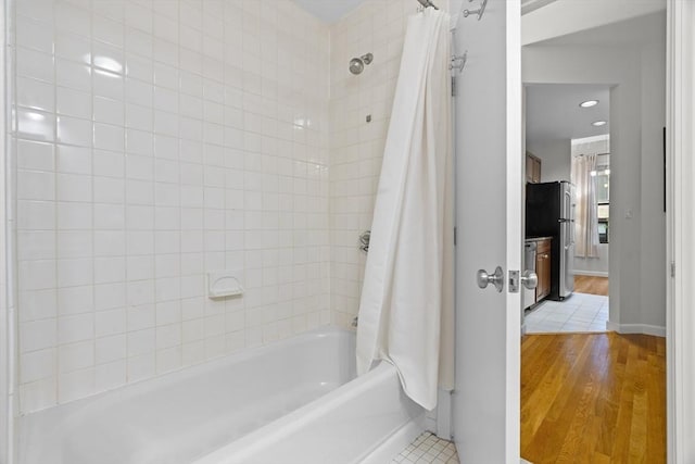 bathroom with baseboards, shower / tub combo, and wood finished floors