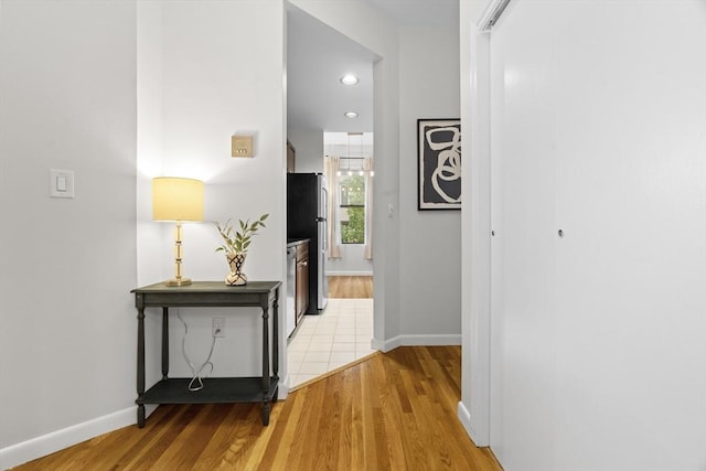 corridor featuring light wood-style floors, baseboards, and recessed lighting
