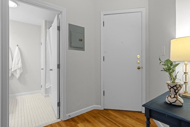 doorway to outside featuring electric panel, wood finished floors, and baseboards