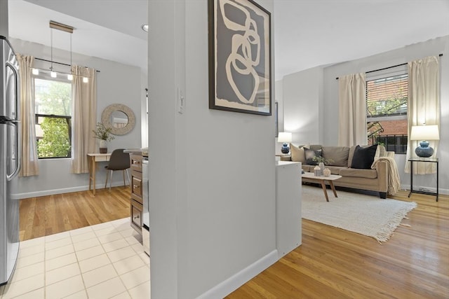 hallway featuring healthy amount of natural light, light wood-type flooring, and baseboards