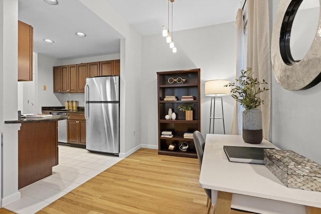 kitchen featuring freestanding refrigerator, brown cabinets, light wood-style floors, recessed lighting, and hanging light fixtures