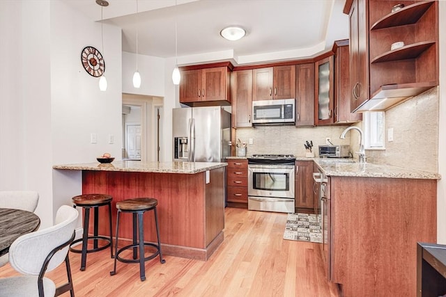 19 Harris St Unit 2, Brookline, MA 02446 - kitchen featuring stainless steel appliances, light wood-style floors, a kitchen bar, light stone countertops, and backsplash