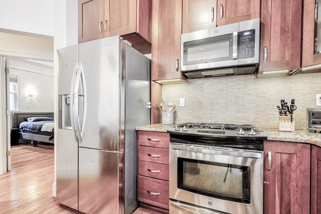 19 Harris St Unit 2, Brookline, MA 02446 - kitchen featuring stainless steel appliances, light wood finished floors, light stone counters, and backsplash