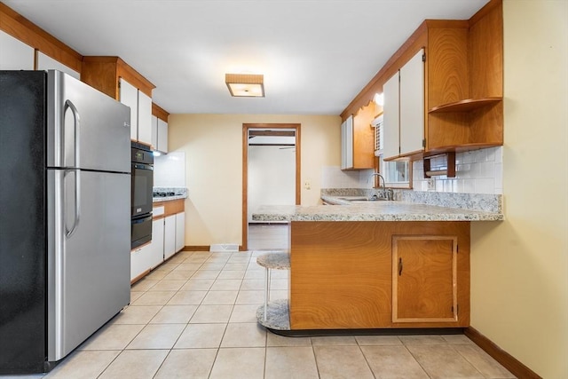 76 N Main St, Bellingham, MA 02019 - kitchen with freestanding refrigerator, a sink, oven, a peninsula, and light tile patterned floors