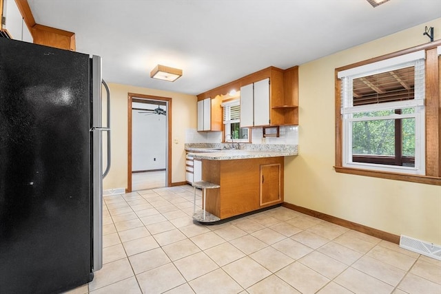 76 N Main St, Bellingham, MA 02019 - kitchen featuring freestanding refrigerator, a peninsula, light tile patterned flooring, and baseboards