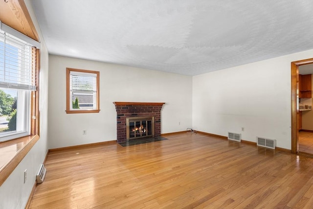 76 N Main St, Bellingham, MA 02019 - unfurnished living room with light wood-style floors, baseboards, a brick fireplace, and a baseboard heating unit