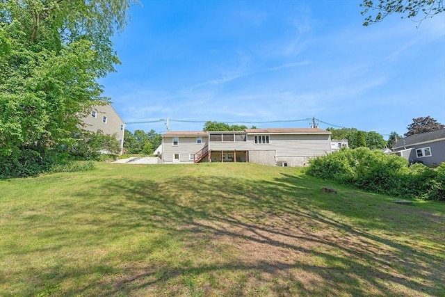 76 N Main St, Bellingham, MA 02019 - rear view of house featuring stairway, a lawn, and a sunroom
