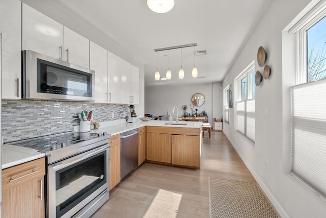 kitchen with tasteful backsplash, a peninsula, visible vents, a sink, and stainless steel appliances