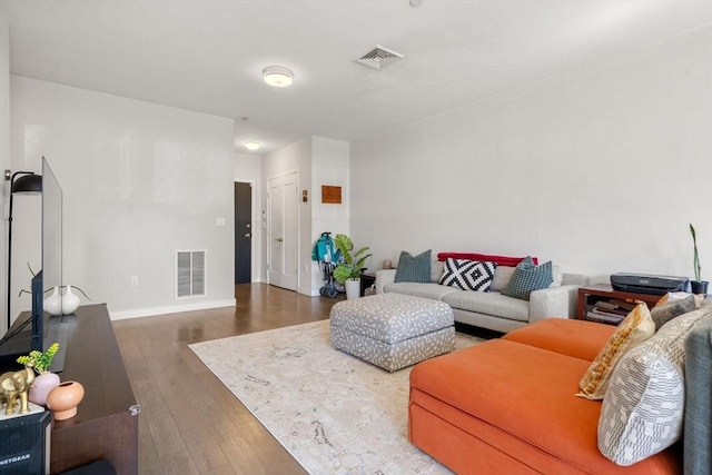 living room featuring visible vents, hardwood / wood-style flooring, and baseboards