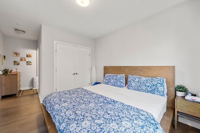 bedroom with a closet, baseboards, and wood finished floors