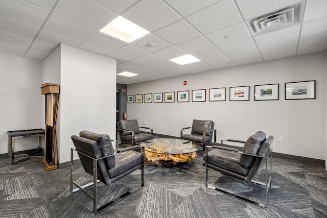 living area featuring carpet, visible vents, baseboards, and a paneled ceiling