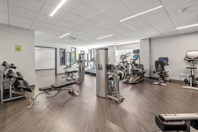 gym featuring baseboards, a paneled ceiling, and wood finished floors