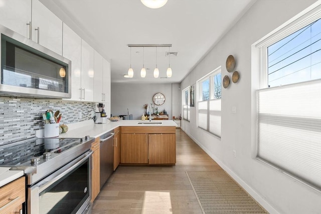 kitchen featuring a peninsula, visible vents, decorative backsplash, stainless steel appliances, and a sink