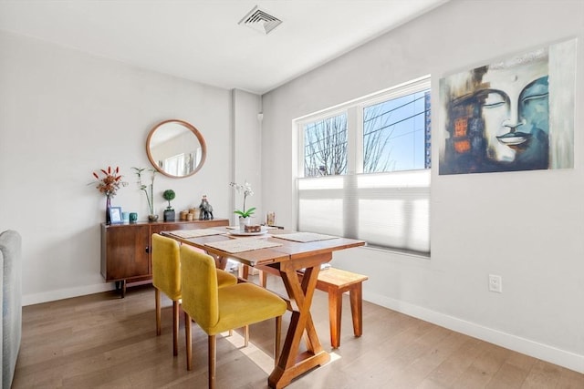 dining space with light wood finished floors, baseboards, and visible vents