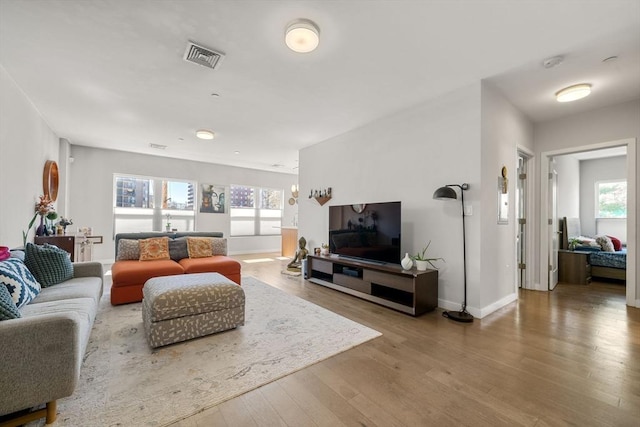 living room with visible vents, baseboards, and wood finished floors