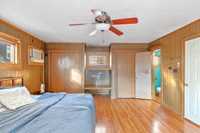 unfurnished bedroom with ceiling fan, connected bathroom, light wood-type flooring, and a wall mounted air conditioner