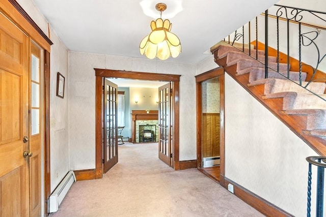 foyer featuring a fireplace, light colored carpet, a baseboard heating unit, and french doors