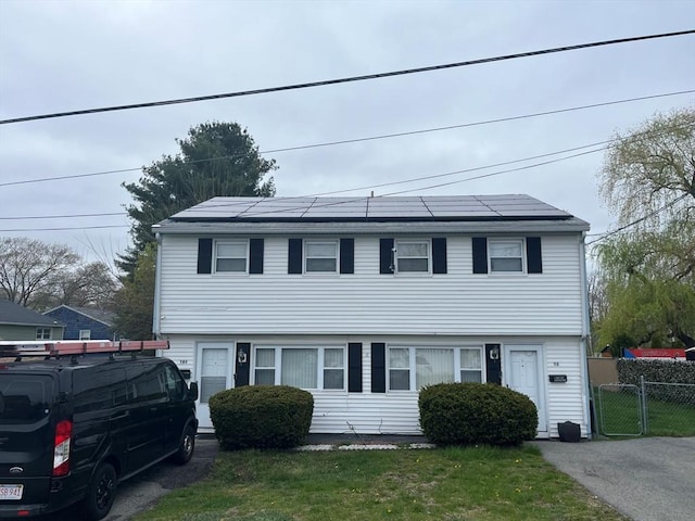 view of front of property featuring solar panels and a front yard