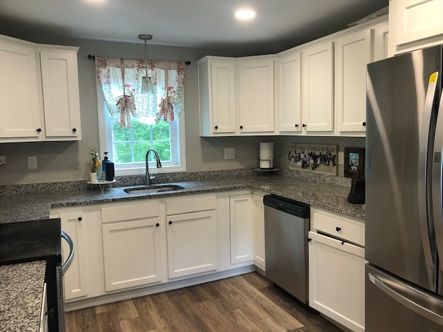 kitchen with white cabinets, dark hardwood / wood-style floors, hanging light fixtures, appliances with stainless steel finishes, and sink