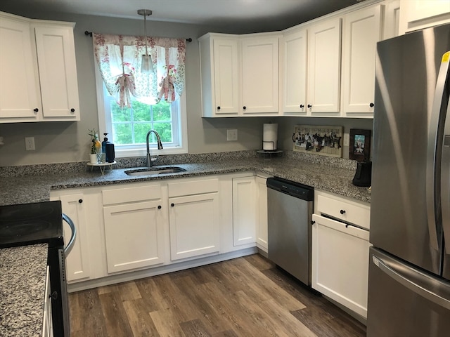 kitchen with appliances with stainless steel finishes, white cabinets, sink, pendant lighting, and dark hardwood / wood-style floors